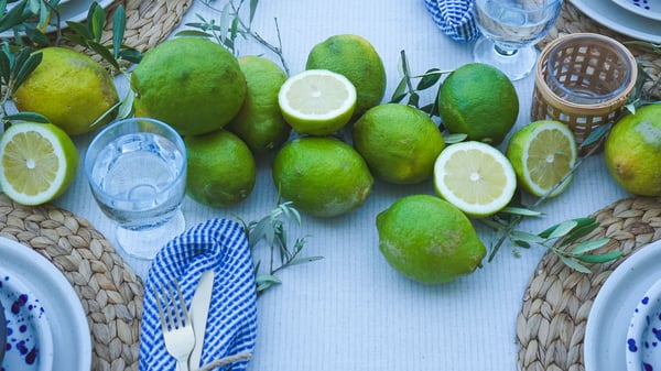 Gedeckter Tisch mit IKEA Silvereda Teller, NATTKLOT Besteck, FRUKTDUVA Kelchglas, blau-weisser Serviette, Limetten, Oliven. Perfekt für mediterrane Sommeressen.