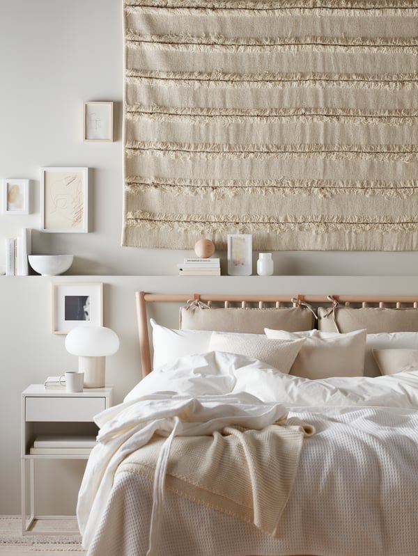 A large PEDERSBORG handcrafted rug hangs above a wooden bedframe in a eco-friendly styled room. With Organic elements throughout.