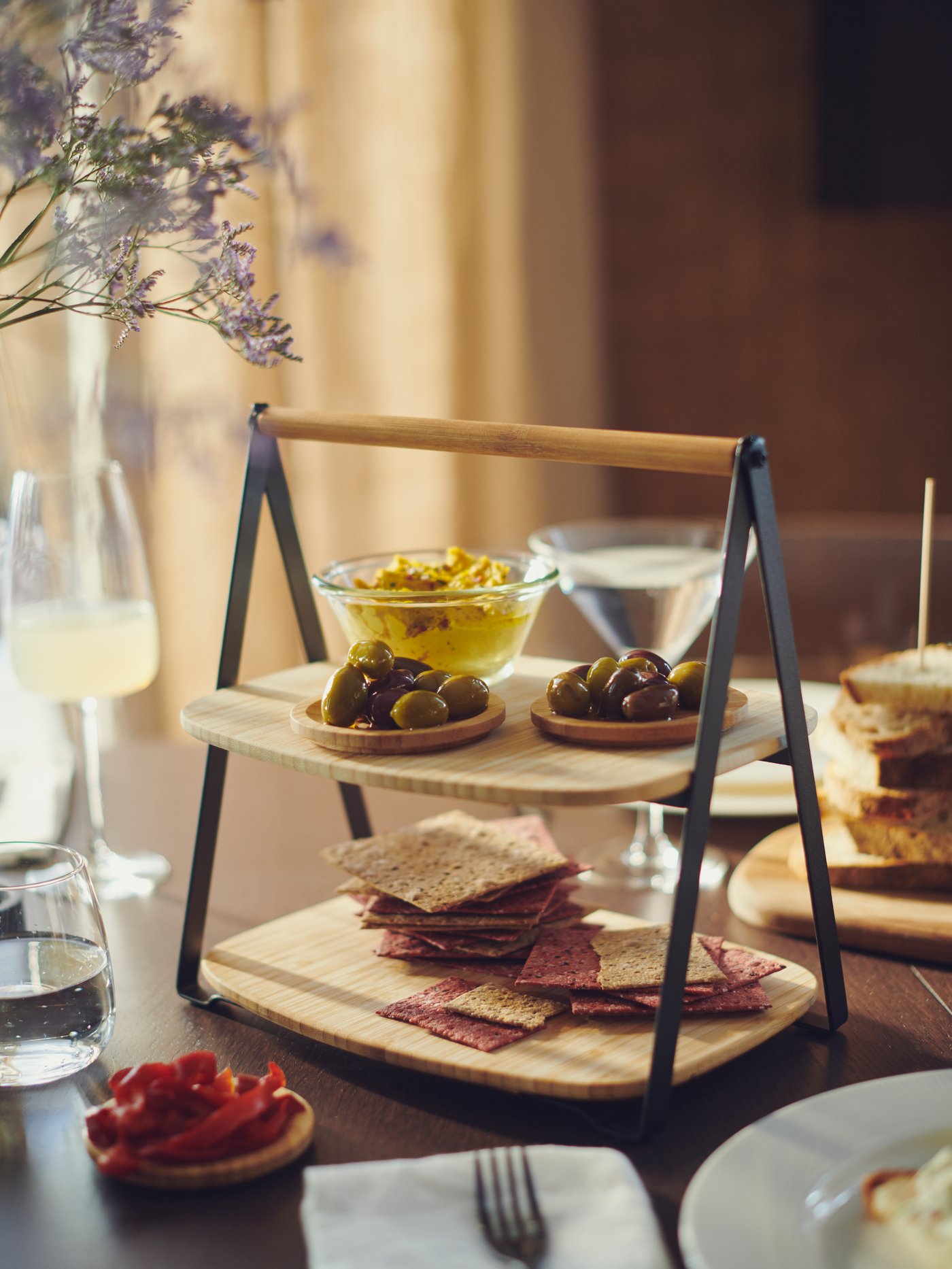 Two-tiered wooden/metal serving tray on a dining table.