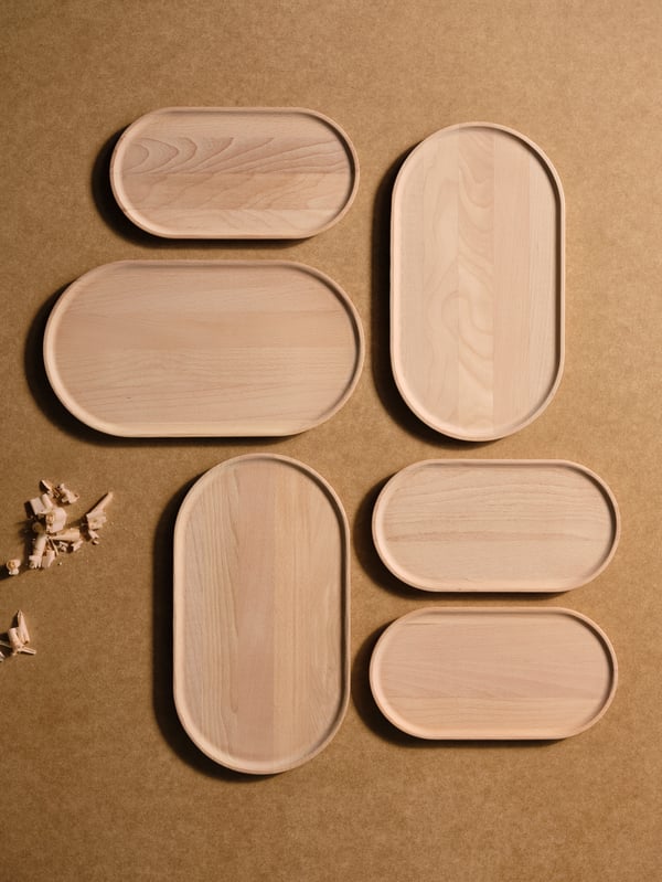 Multiple pieces of the SMÖRLING set-of-two serving trays are symmetrically arranged on a wooden surface with wood shavings.