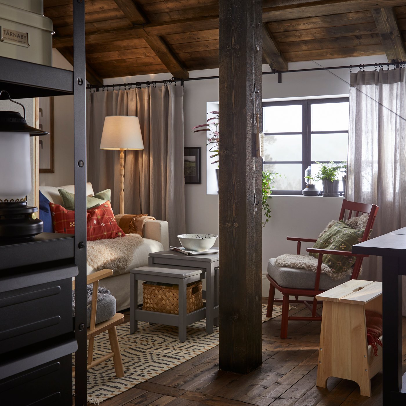 A wooden beam divides a room with a NORDVIKEN extendable table on one side and a HYLTARP sofa on the other.