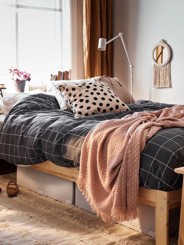 Una habitación con una cama NEIDEN con ropa de cama VITKLÖVER y mantas HORNMAL.