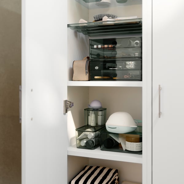 A bathroom with a grey VISSLAÅN mini chest featuring two drawers, storing various toiletries and decorative items.