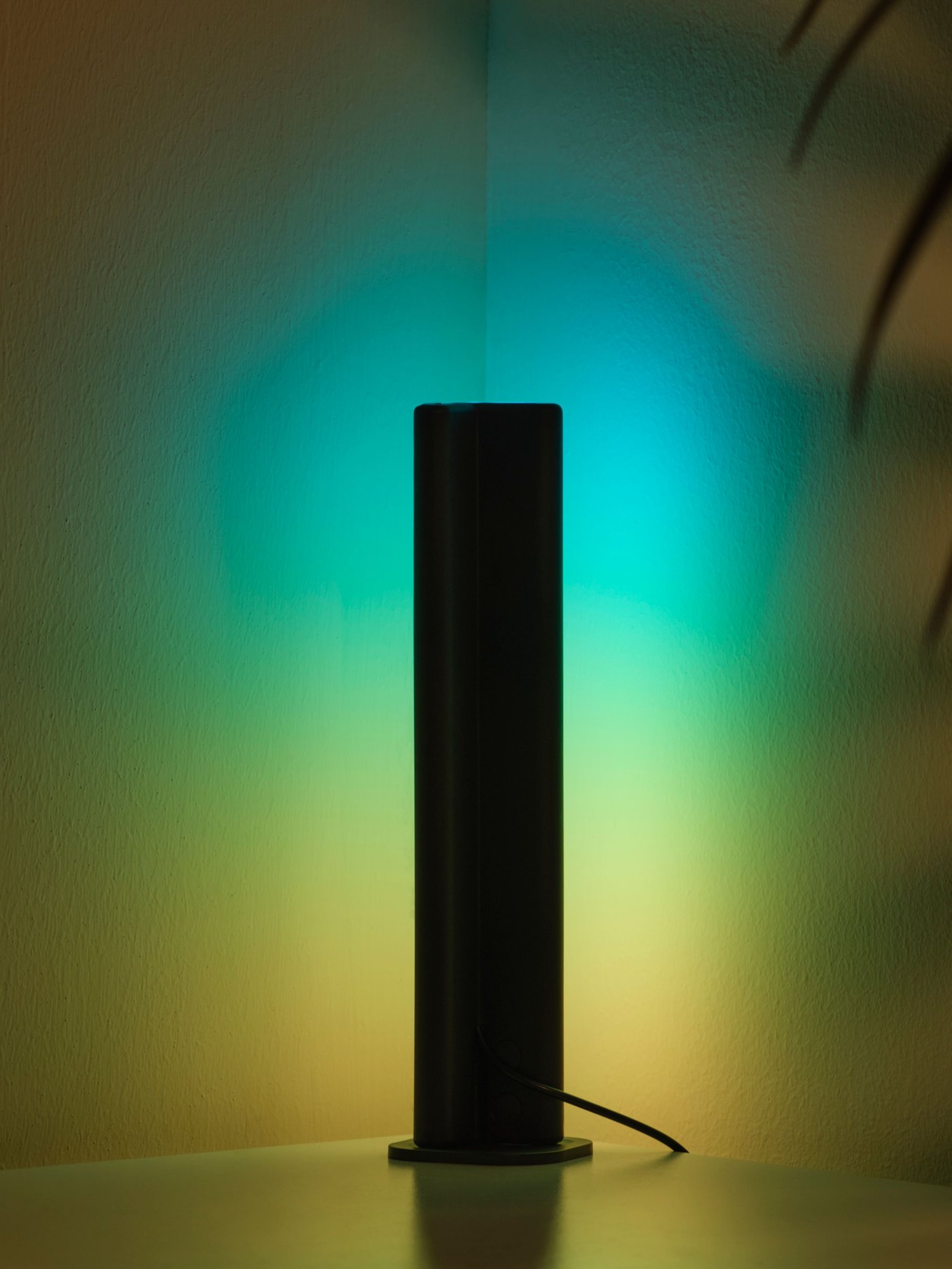 A dimmable SKAFTSÄRV LED decoration lighting with blue and yellow light shining on the wall.