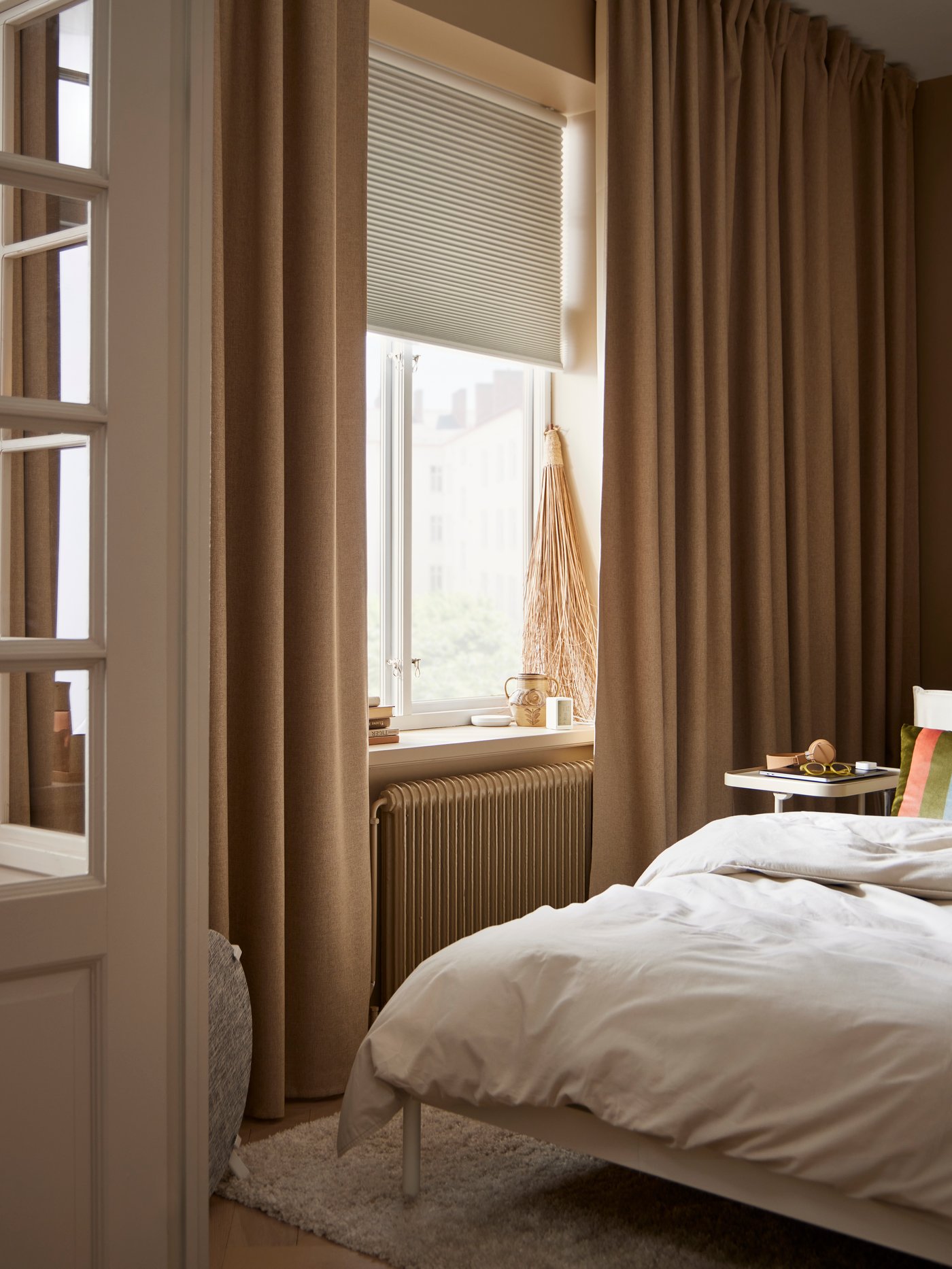 A smart wireless/battery-operated white TREDANSEN block-out cellular blind in the bedroom