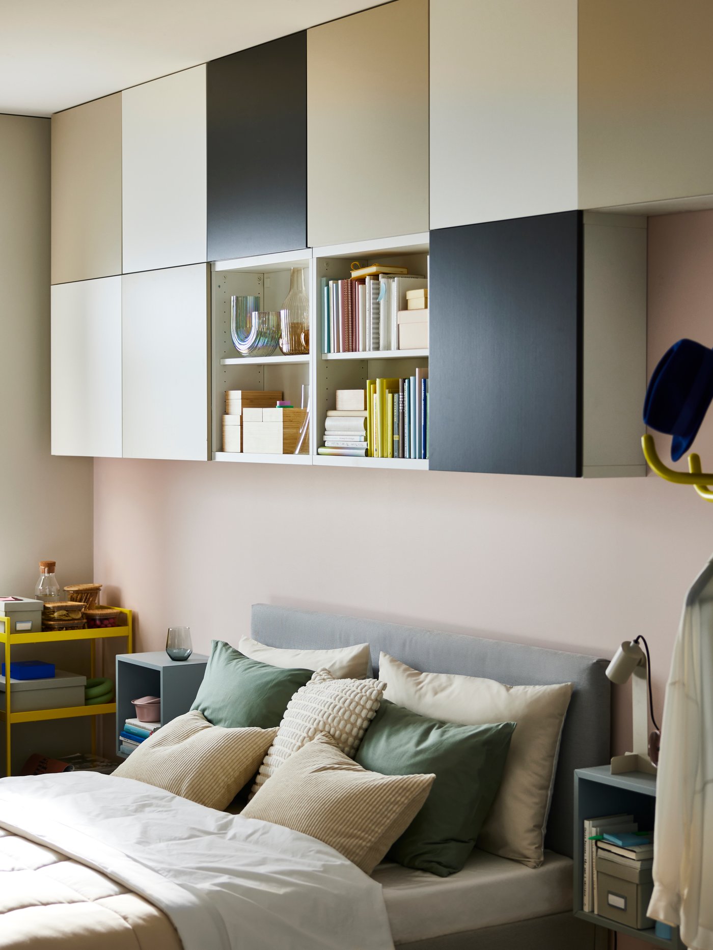 Elf BESTÅ-Korpusse an einer Wand. Neun davon haben LAPPVIKEN Türen in Weiß, Dunkelgrau und Hellgrau-Beige; die anderen beiden sind offen. Sie hängen über einem Bett im Schlafzimmer. 