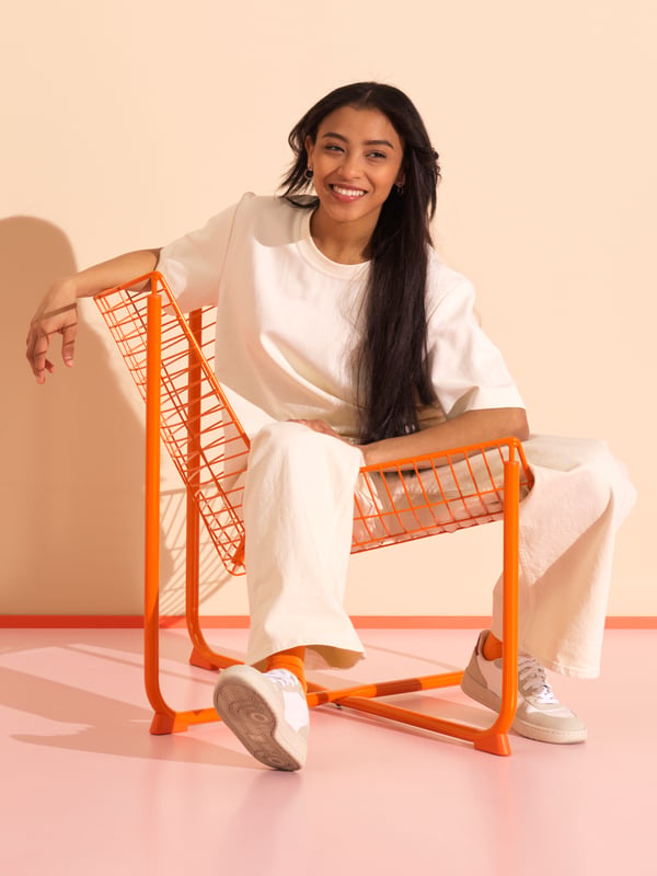 A girl sits on an orange SKÅLBODA armchair.

