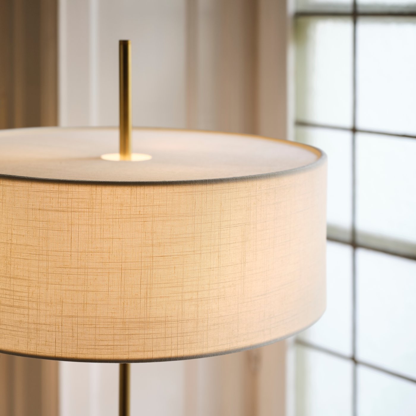 A close-up of a white textile/brass-plated STOCKHOLM 2025 table lamp.