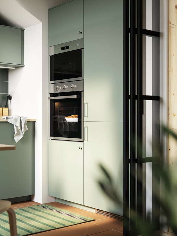 A kitchen with grey green NICKEBO fronts has built-in appliances and a SUPERKALL fridge/freezer with the same style front.