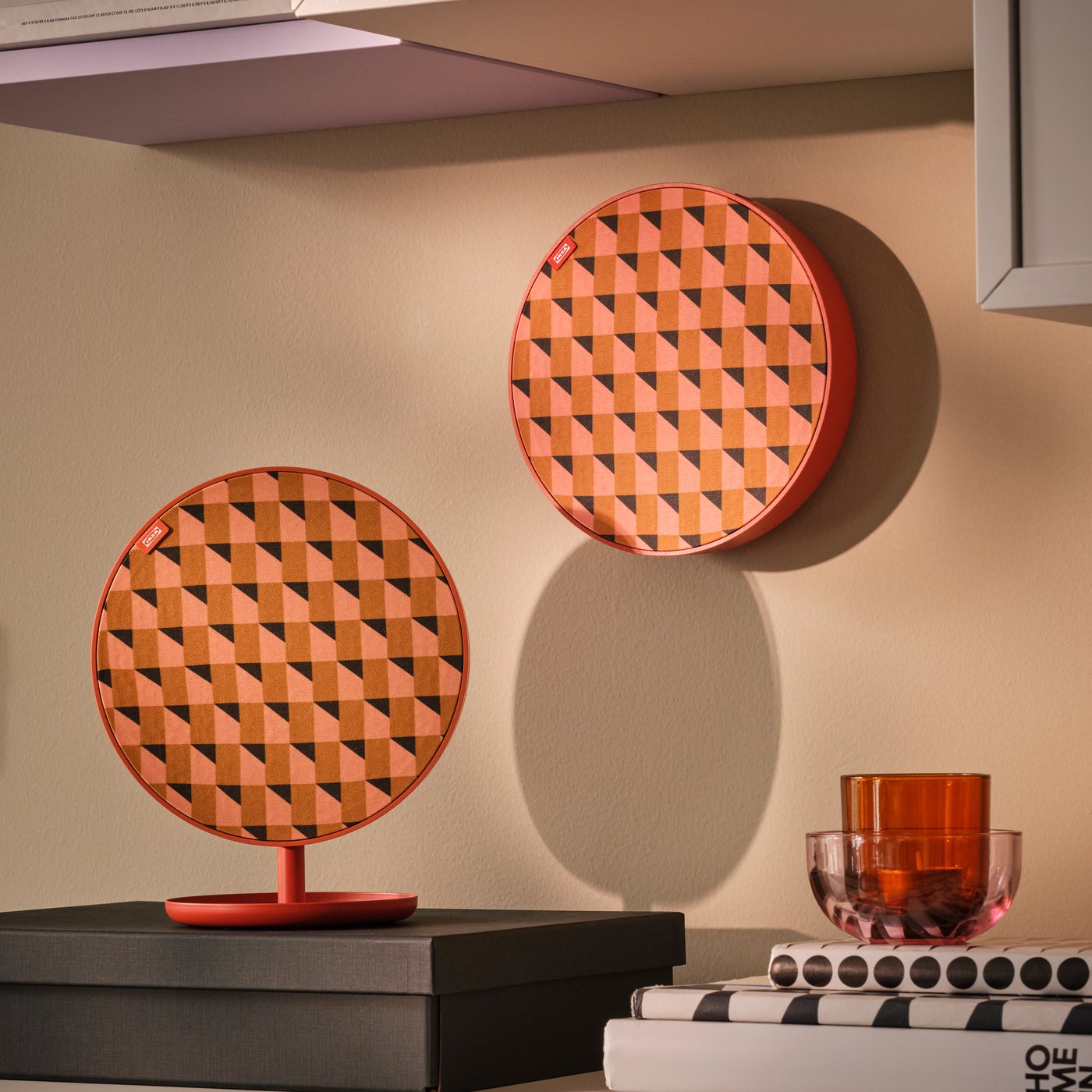 Angle d’un séjour avec deux haut-parleurs Bluetooth portables SOLSKYDD orange, l’une sur un support et l’autre au mur.