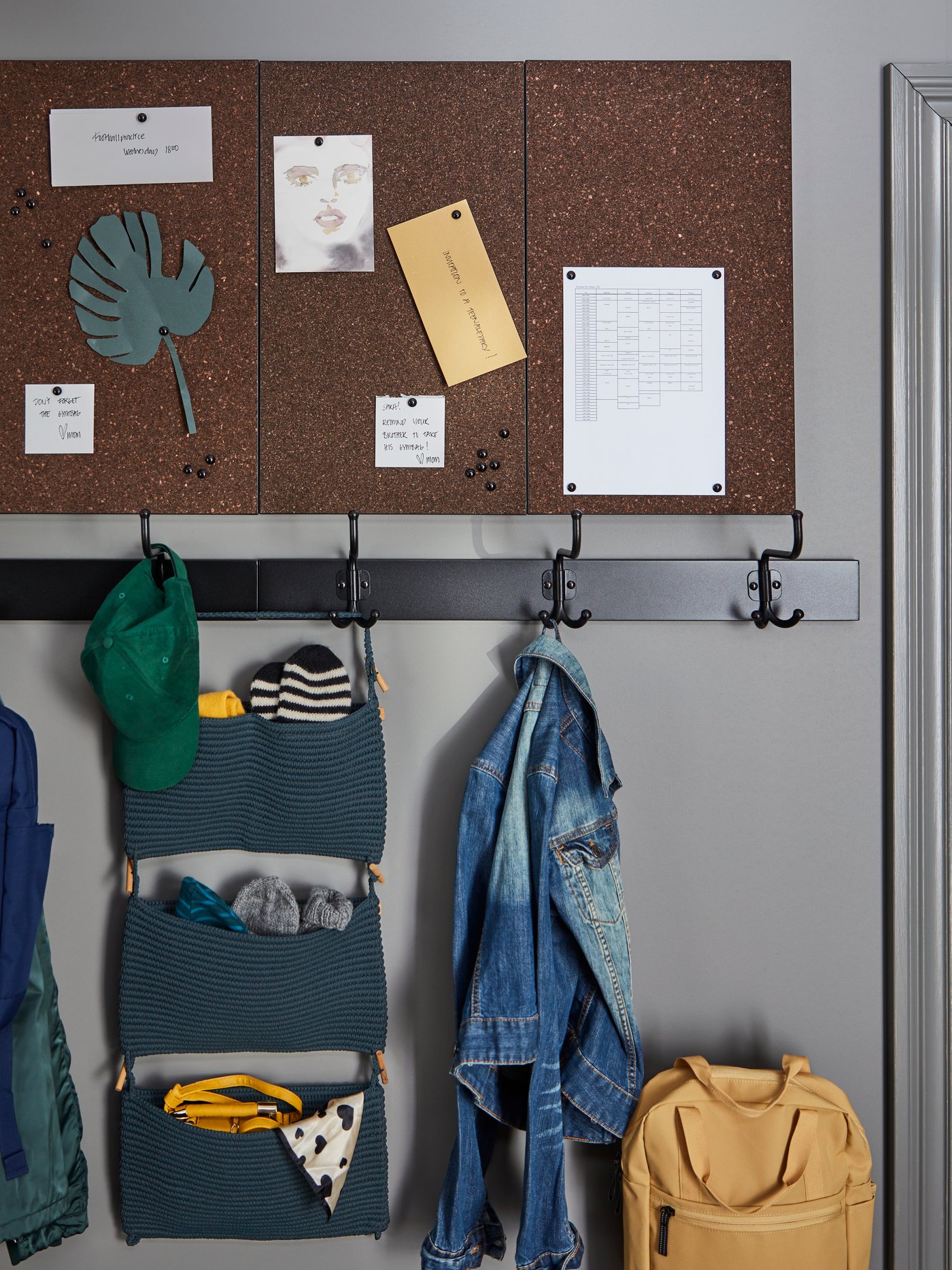 A PINNIG hook rack on a grey wall holding a jacket, hat and NORDRANA hanging storage, with a SVENSÅS memo boards above.