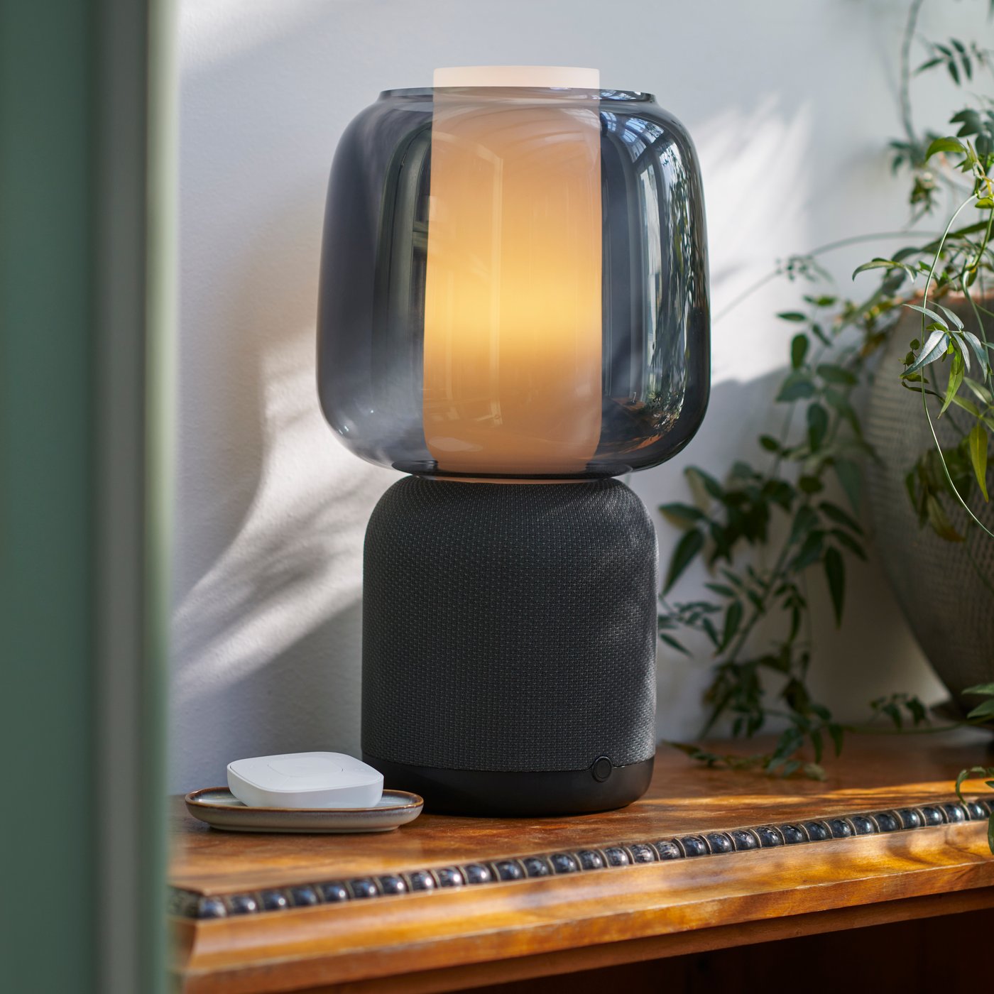 Eine schwarze Symfonsik Lampe / Lautsprecher steht auf einem Sideboard