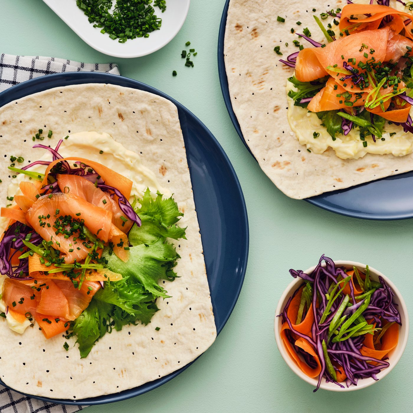 GRÄDDAT blødt tyndt fladbrød med SJÖRAPPORT koldrøget laks, salat og lilla kål, serveret på et bord med ekstra pynt.