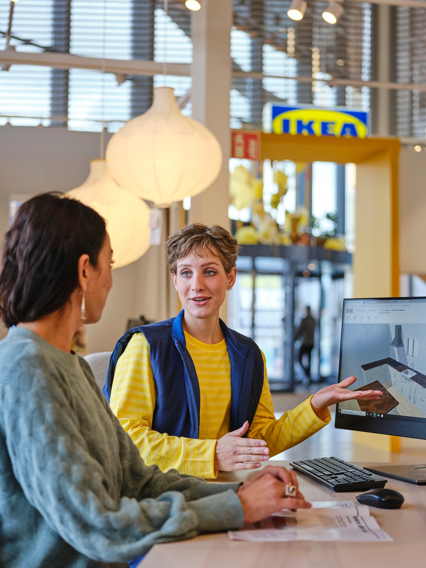 An IKEA planning specialist assisting a women with planning a kitchen.