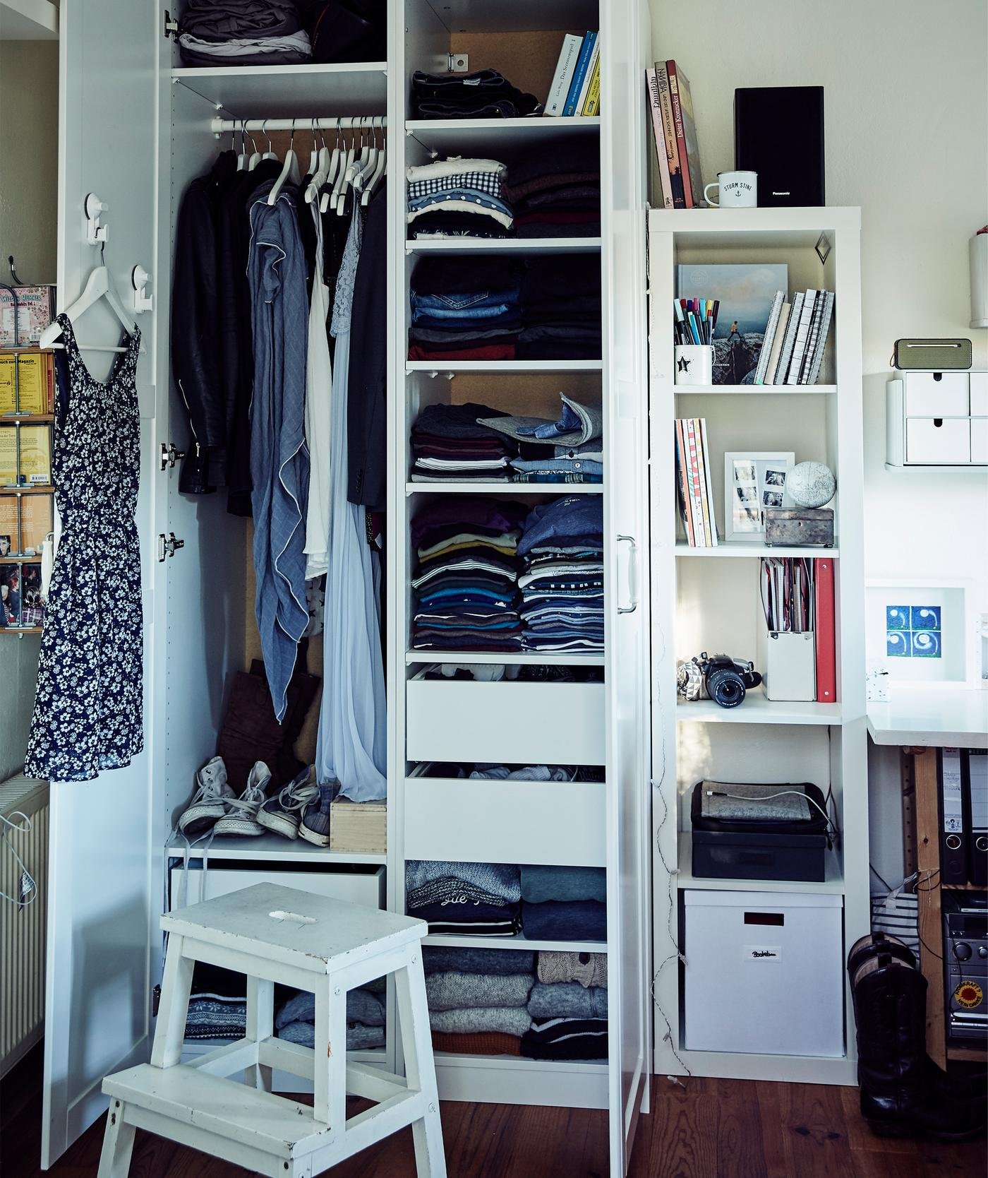 Kleidung auf Regalböden und auf der Stange in Stines PAX Kleiderschrank in Weiss mit FORSAND Fronten in Weiss.