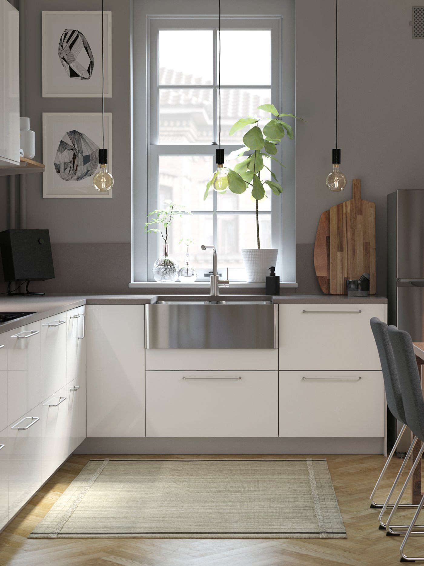A light-filled kitchen with white shiny drawer fronts, grey walls, a wooden table, and a stainless steel sink.