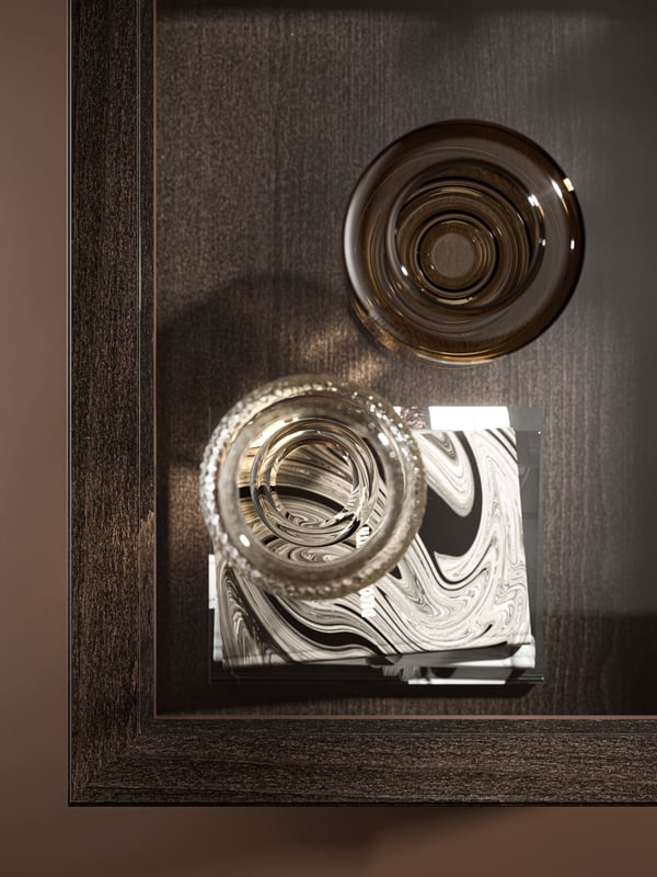A dark-brown-stained IDANÄS coffee table with vases on the tabletop and books visible through its glass top.