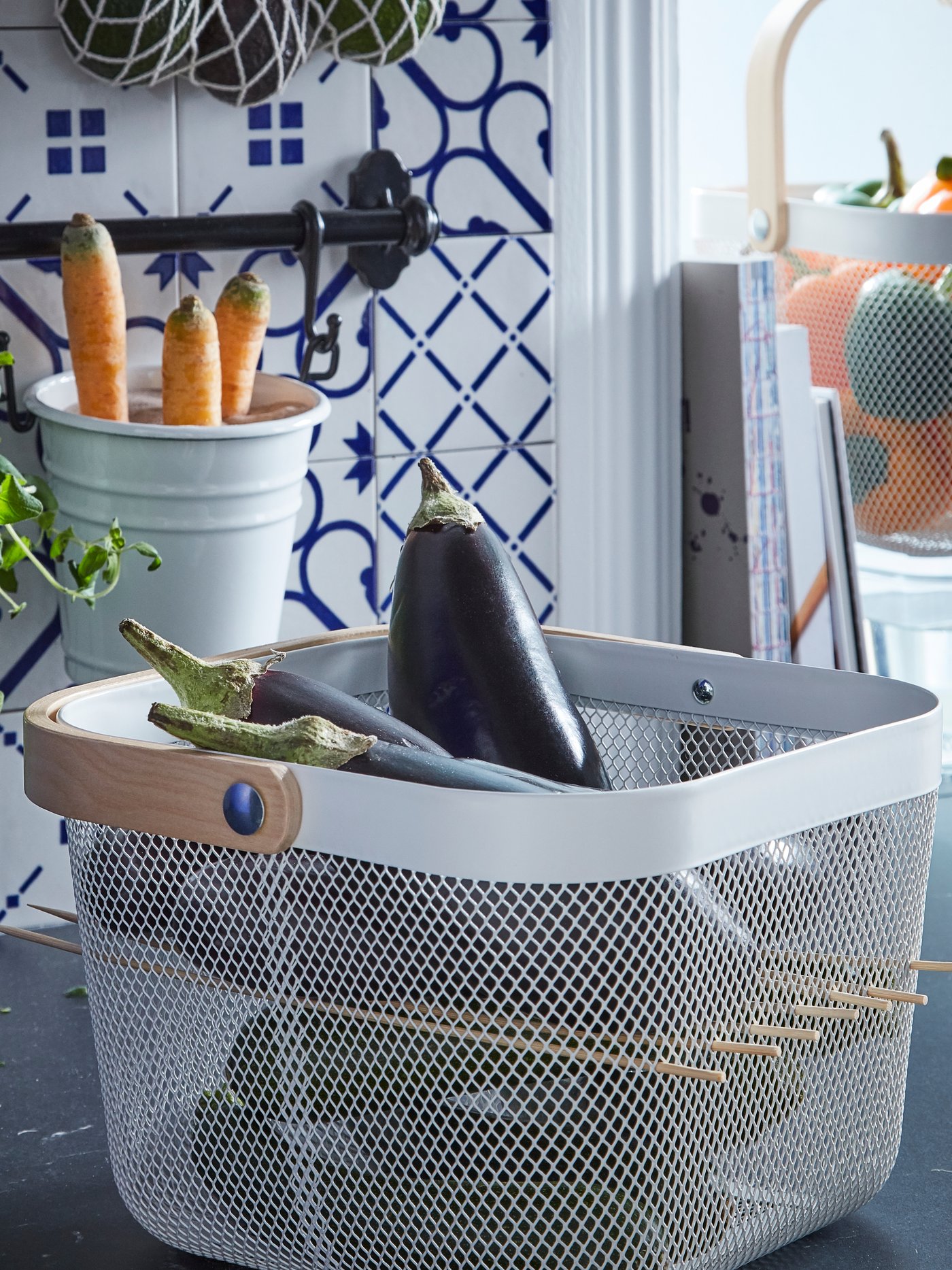 A RISATORP basket, cube-shaped, full of aubergines, and perforated by skewers to create a shelf or partition halfway up.