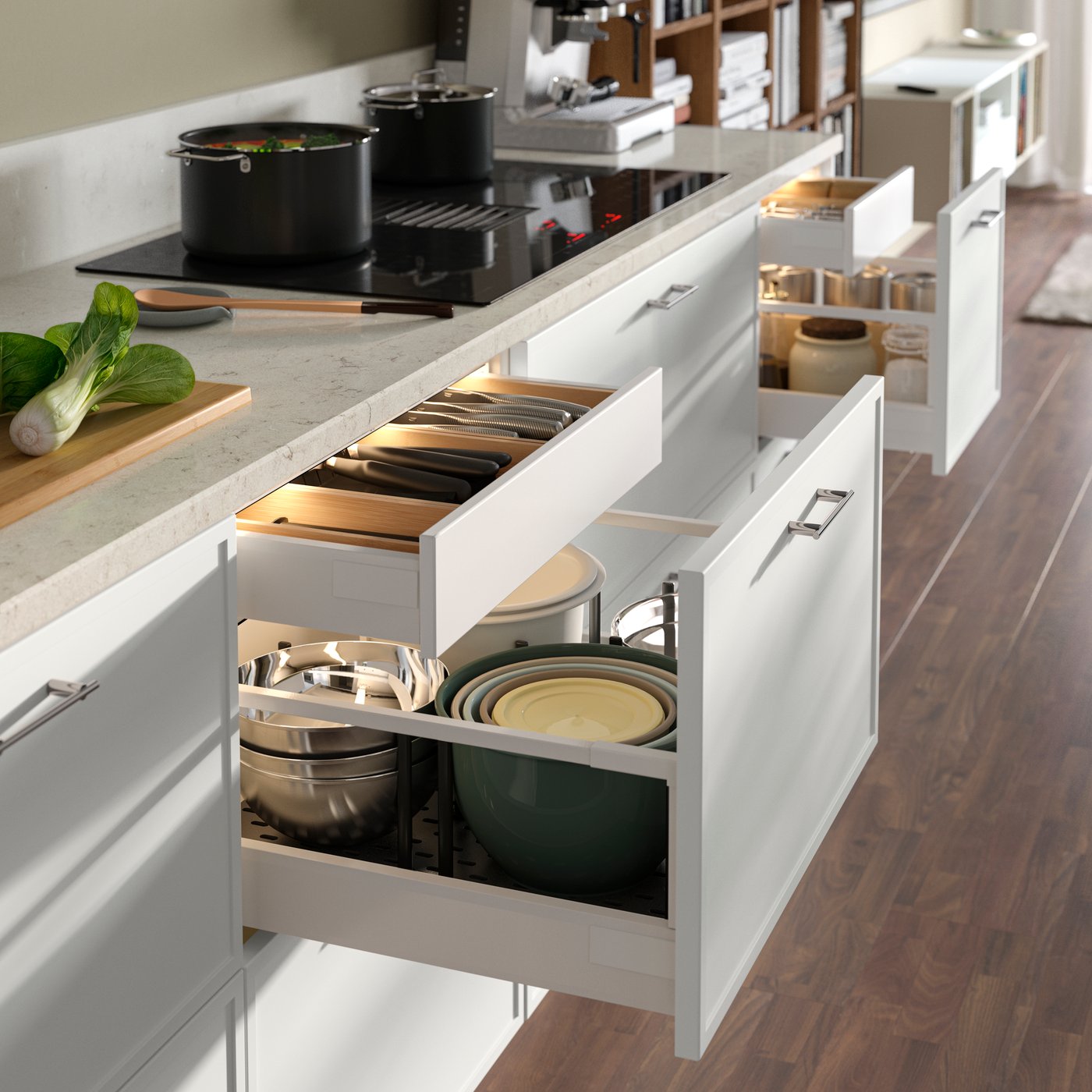 A kitchen with white SEKTION base cabinets features multiple drawers and with cookware displayed and utensils organised.