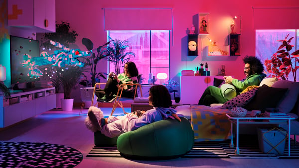 Gamers sit together in an atmospherically lit living room playing on handy gaming furniture
