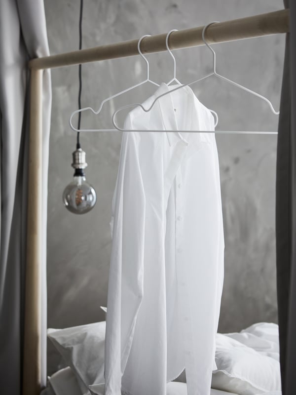 GJÖRA bedframe in birch with three white STAJLIG hangers, one holding a white shirt, hanging on the bedframe.