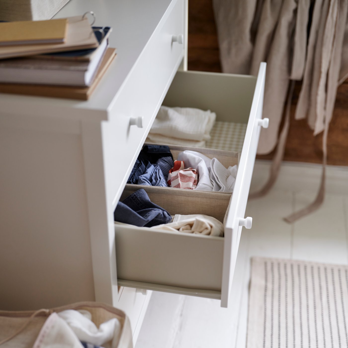 Dans un décor de chambre à coucher, commode 3 tiroirs GULLABERG avec un tiroir ouvert révélant des vêtements bien pliés.