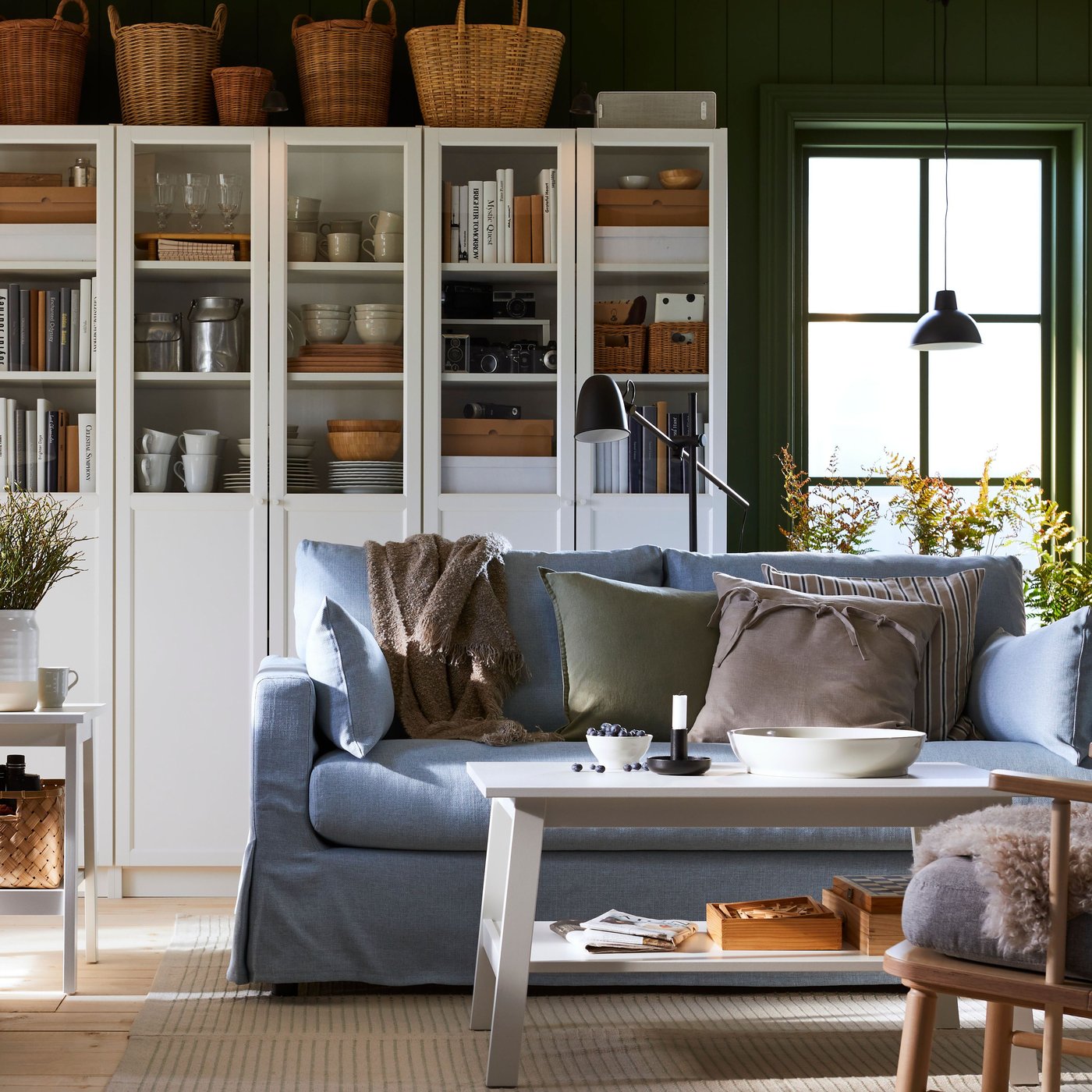 Es ist ein Wohnzimmer mit BILLY Bücherregalen, einem hellblauen HYLTARP Sofa und einem LUNNARP Wohnzimmertisch.