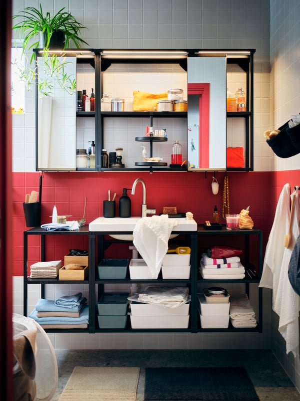 Une salle de bain au carrelage rouge et blanc avec une grande combinaisons ENHET avec des rangements ouverts, contenant des accessoires bien rangés.