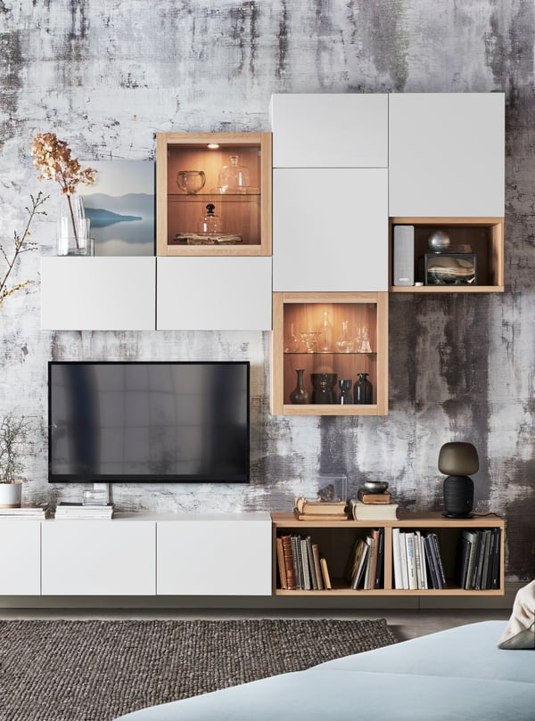 A living room with a BESTÅ storage combination with glass doors with light grey-beige clear glass, and a workstation.