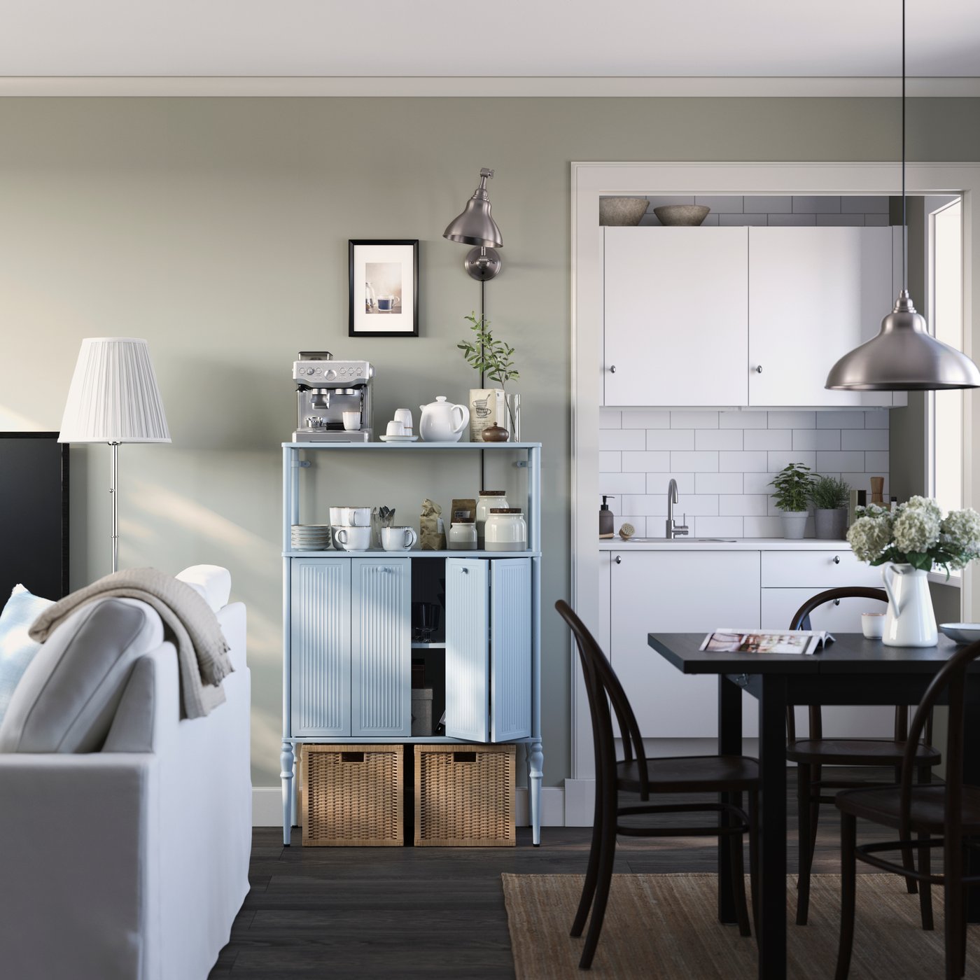 Pièce lumineuse dans laquelle un meuble SÅGMÄSTARE chargé d’accessoires pour le café se niche entre le canapé et le coin repas.
