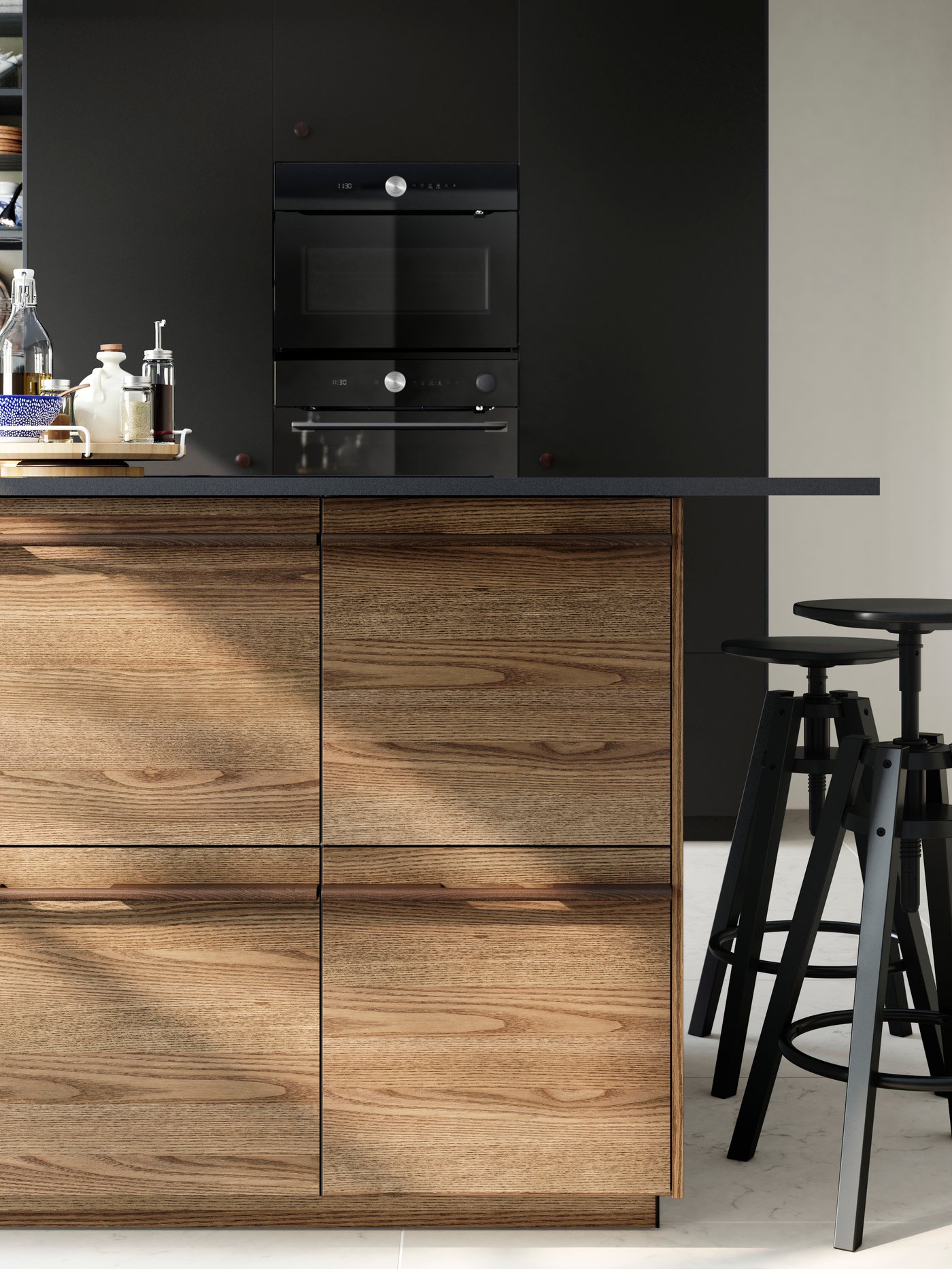 Una cocina con isla con frentes efecto madera. La cubierta de la isla es negra y tiene un organizador de cubierta.