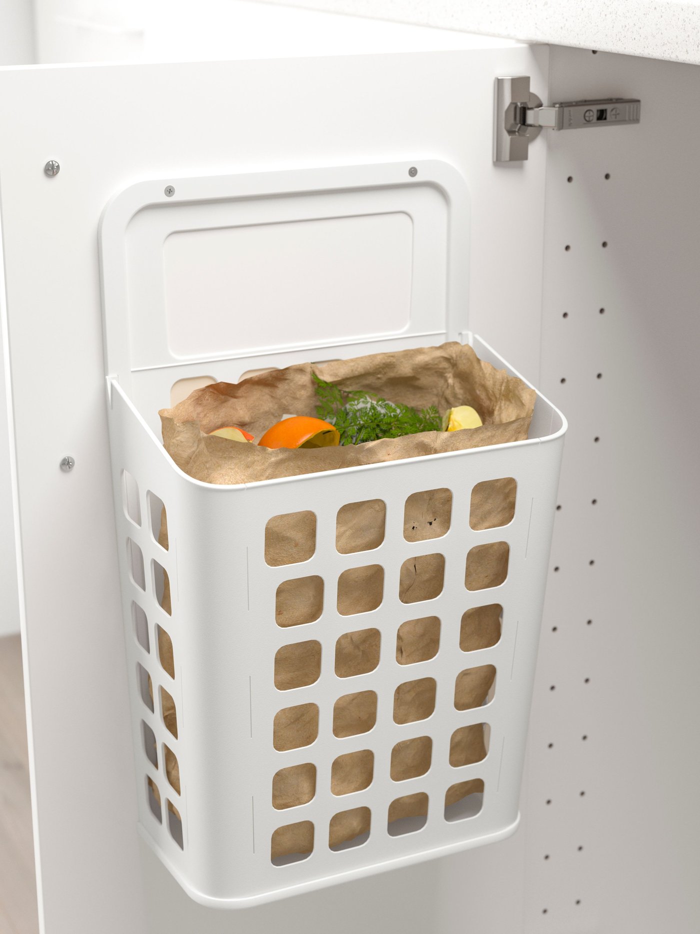 A white VARIERA waste bin lined with a brown paper bag hanging on the inside of an white base cabinet door that is wide open.