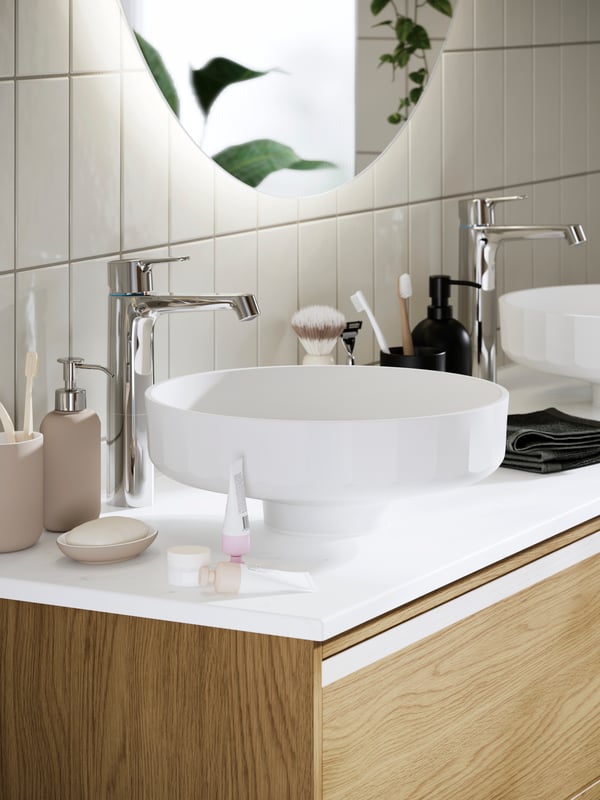 Bathroom counter with a LERSJÖN countertop wash-basin, chrome tap, soap dispenser, and skincare items on a white surface.