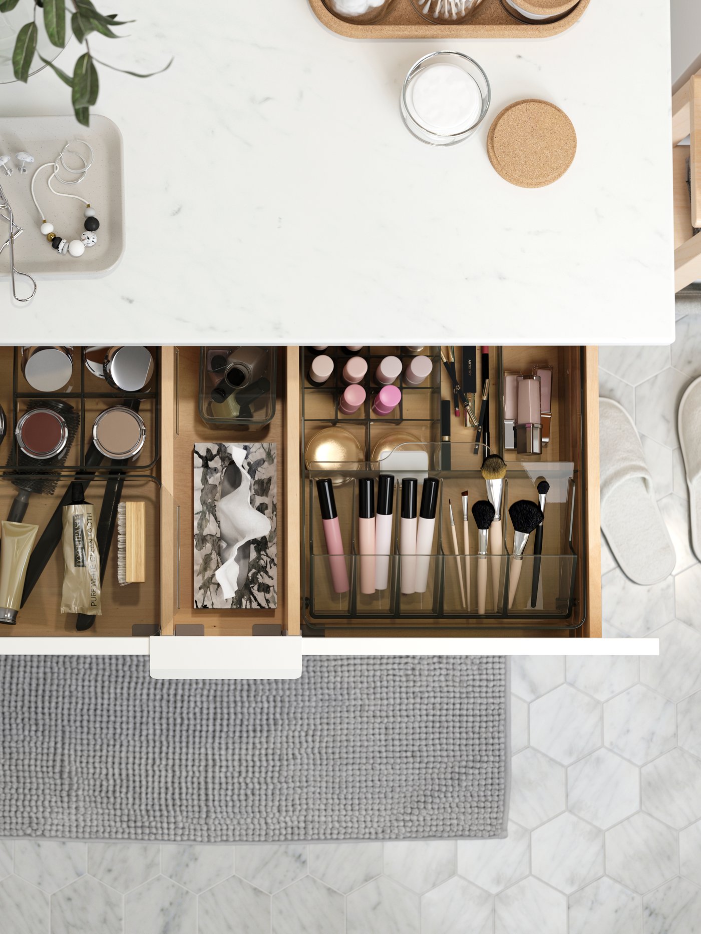 Un mueble de baño con un cajón abieto mostrando artículos de maquillaje ordenados en cajas y separadores.