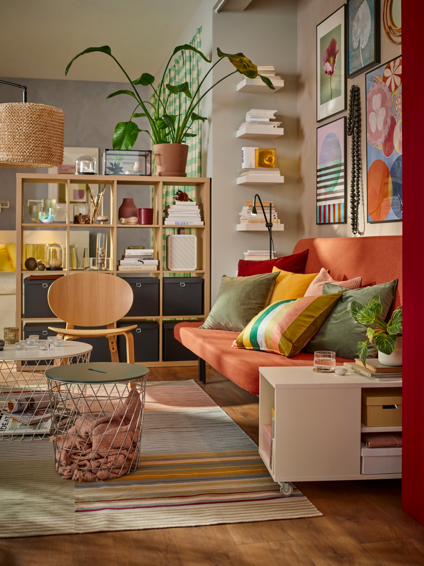 Un living con un sofá y de fondo un estante KALLAX con decoraciones.