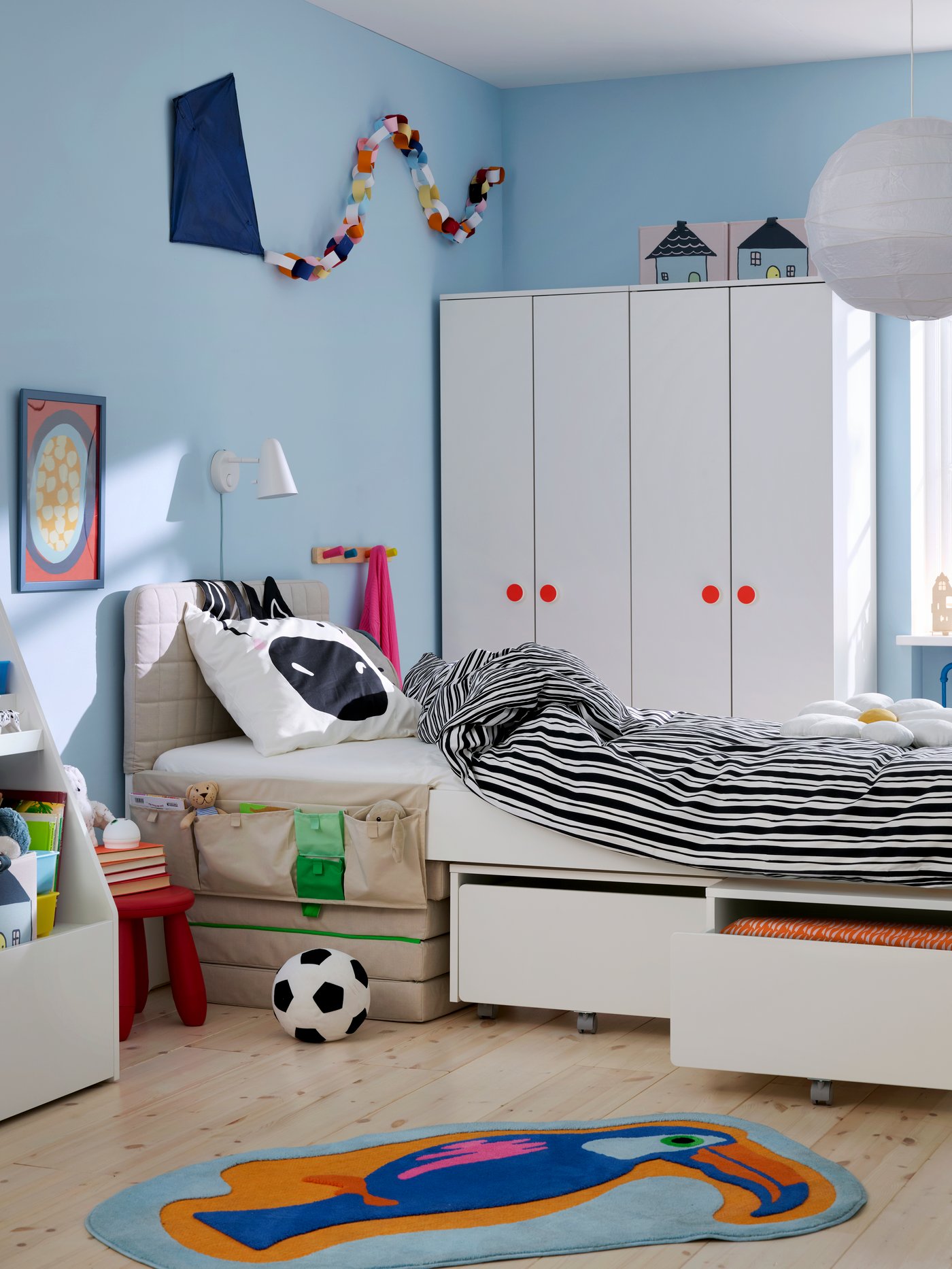 Full view of children’s room with blue walls, the bed in the middle, wardrobes in the back, NATTHÄGER rug on the floor.