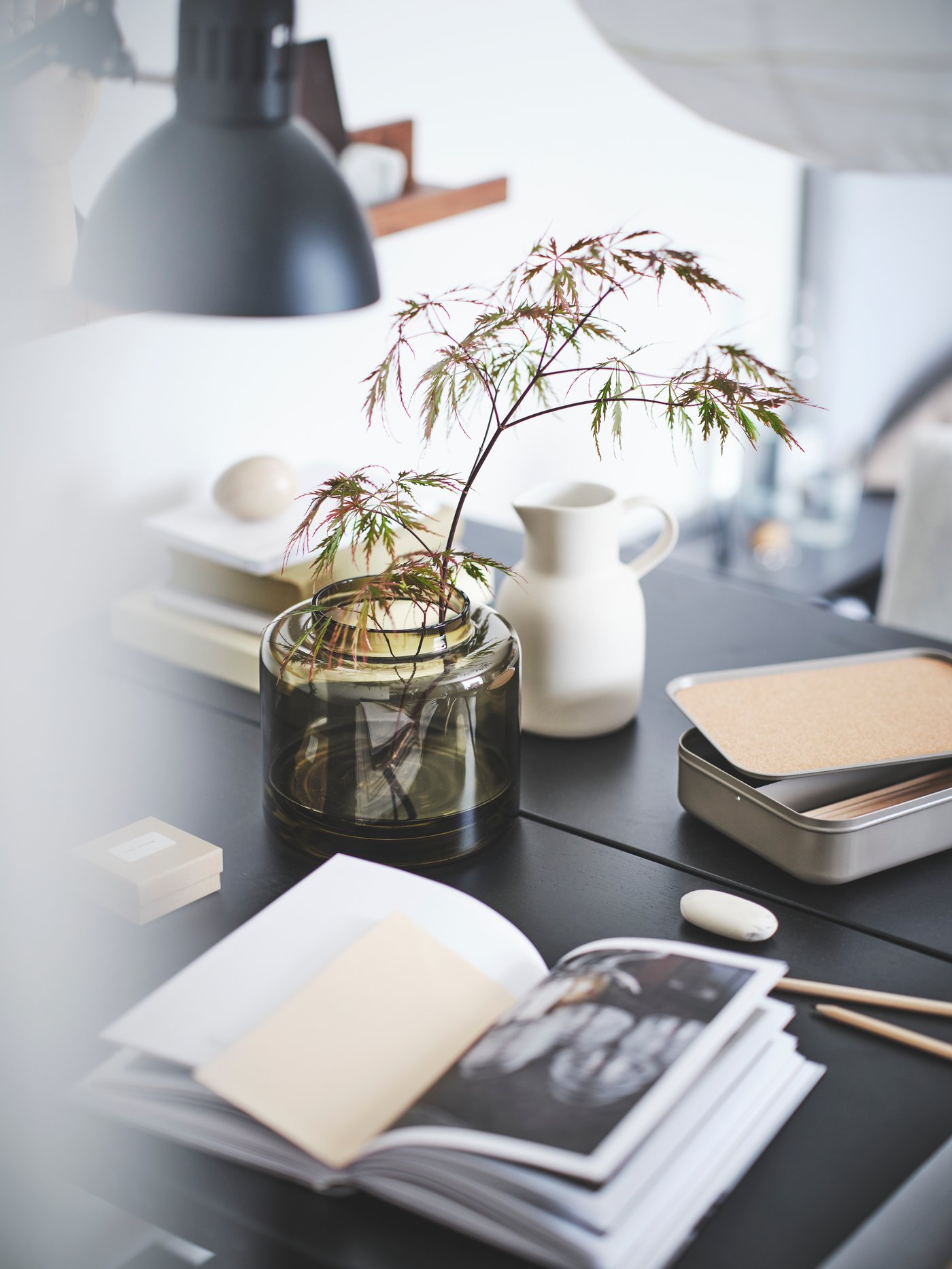 Un pichet SLÄTTIKA blanc posé sur une table parmi d’autres objets de décoration. 