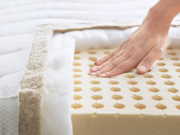 Gros plan sur une main qui teste le confort d’un matelas IKEA.