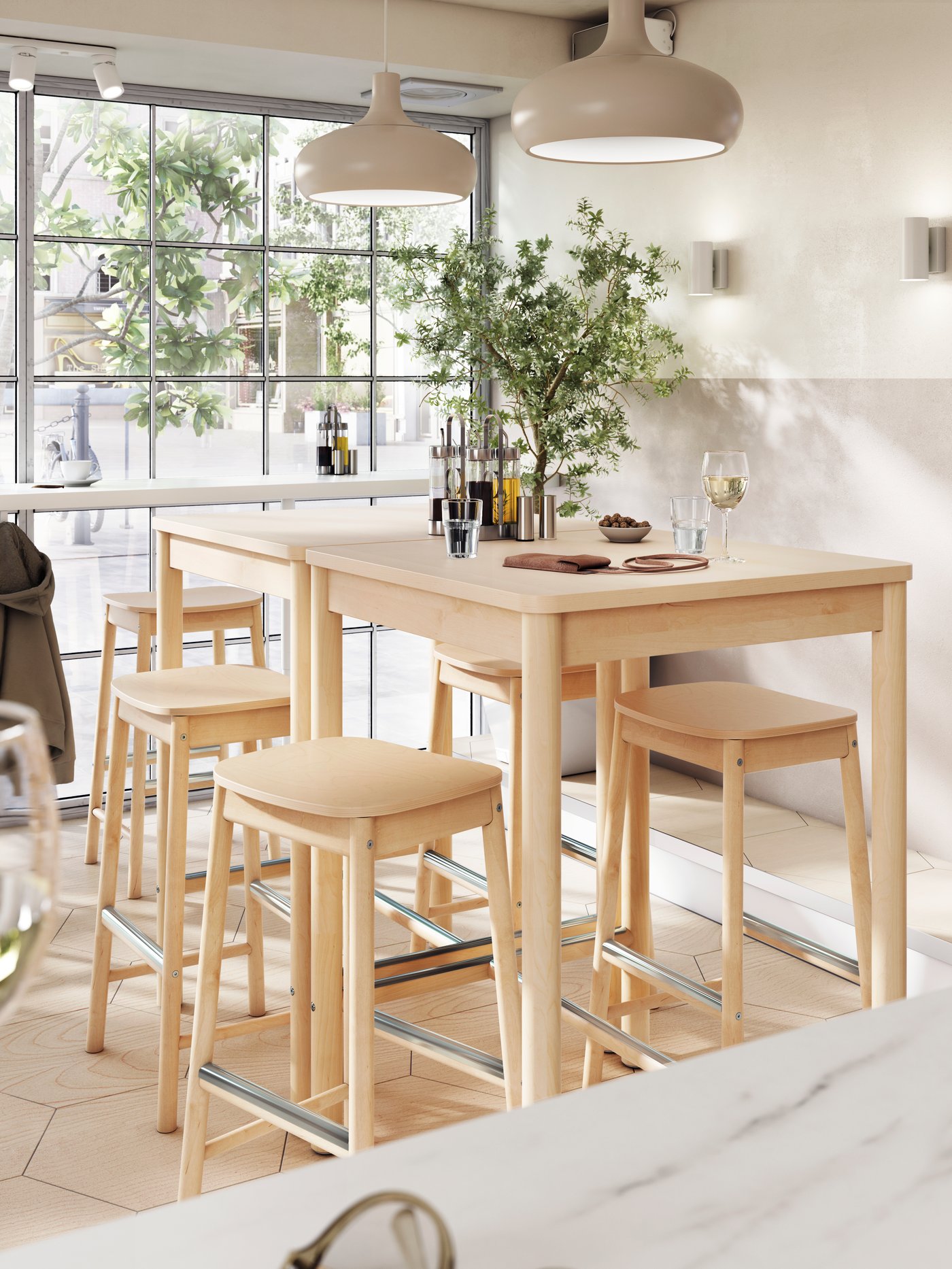 Cinque sgabelli bar RÖNNINGE in betulla attorno a due tavoli alti con sopra bicchieri di vino e acqua, vicino a una finestra - IKEA