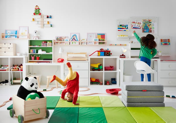 2 Kinder spielen in einem Kinderzimmer in weiß und grünen Farben.