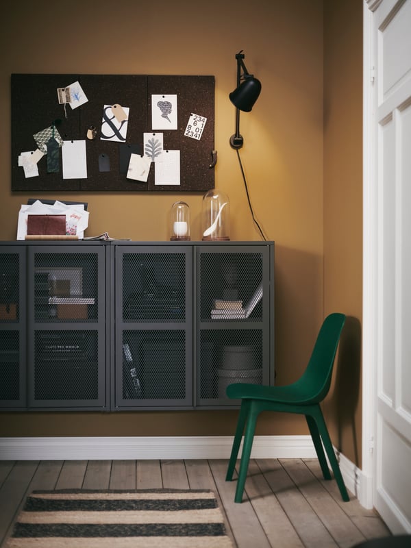 Une entrée avec des armoires avec portes IVAR, des tableaux d’affichage SVENSÅS et une lampe de travail/murale SKURUP fixée au mur.