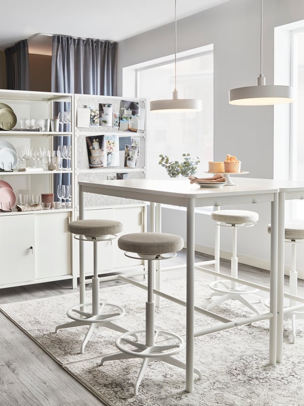 TOMMARYD bar table and LIDKULLEN bar chairs around it in white with two NYMANE pendant lamps hanging above them in a dining area on top of a carpet.