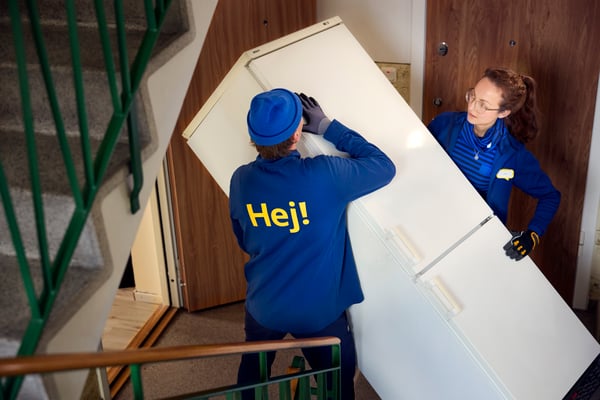 Two IKEA employees carrying a refrigerator.