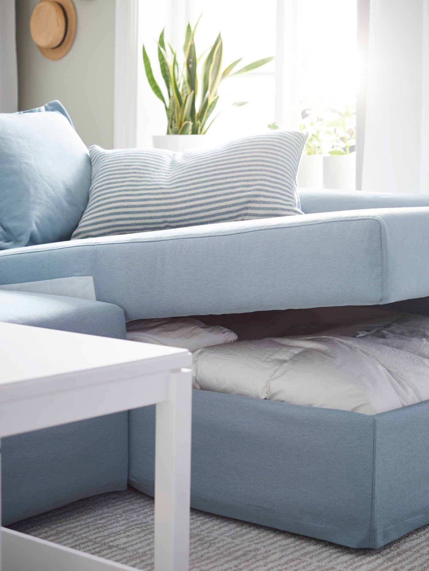Opened IKEA HOLMSUND corner sofa-bed, in Orrsta light blue, with storage space under the chaise longue for bedding.