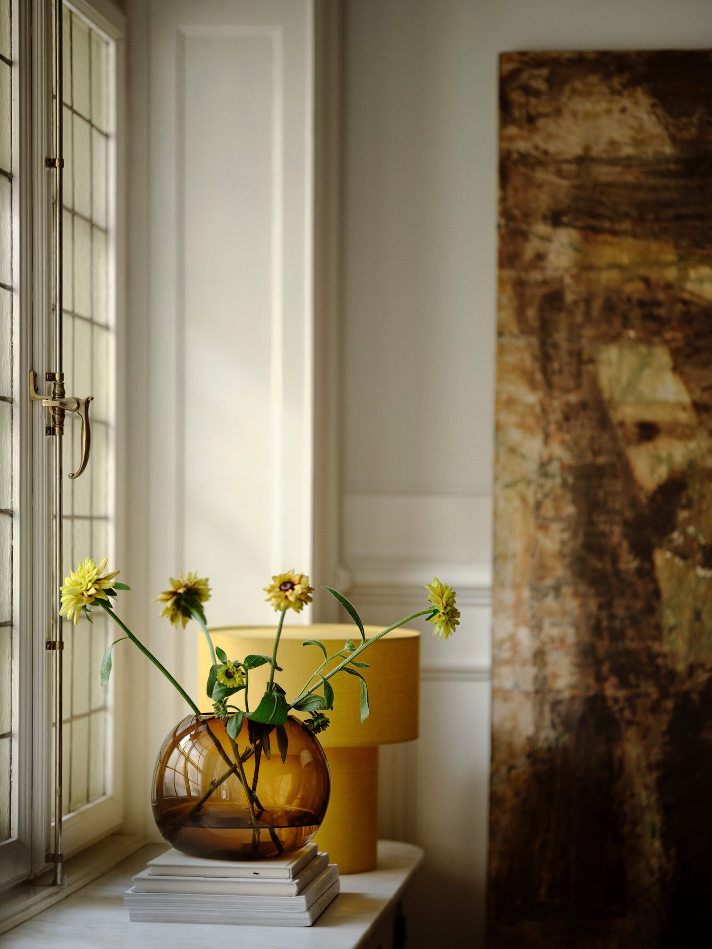Mouth-blown brown STOCKHOLM 2025 glass vase and yellow table lamp with window from the collection.