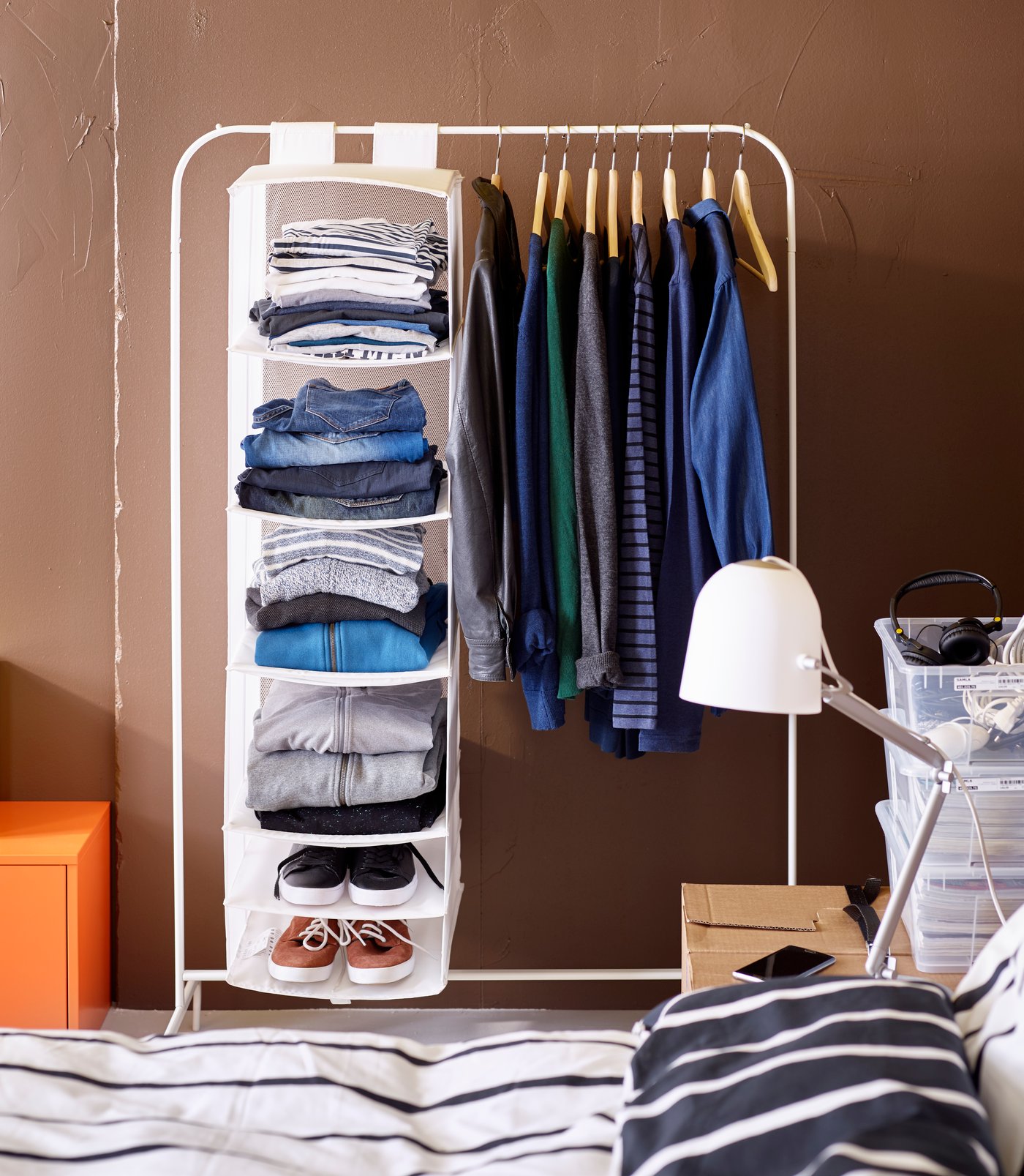 A white MULIG clothes rack with a white SKUBB storage with 6 compartments and clothes hanging on hangers.