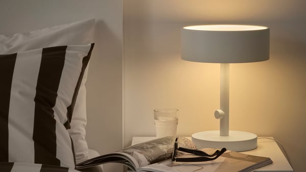 Vit NYMÅNE bordslampa på ett vitt sängbord i sovrummet.