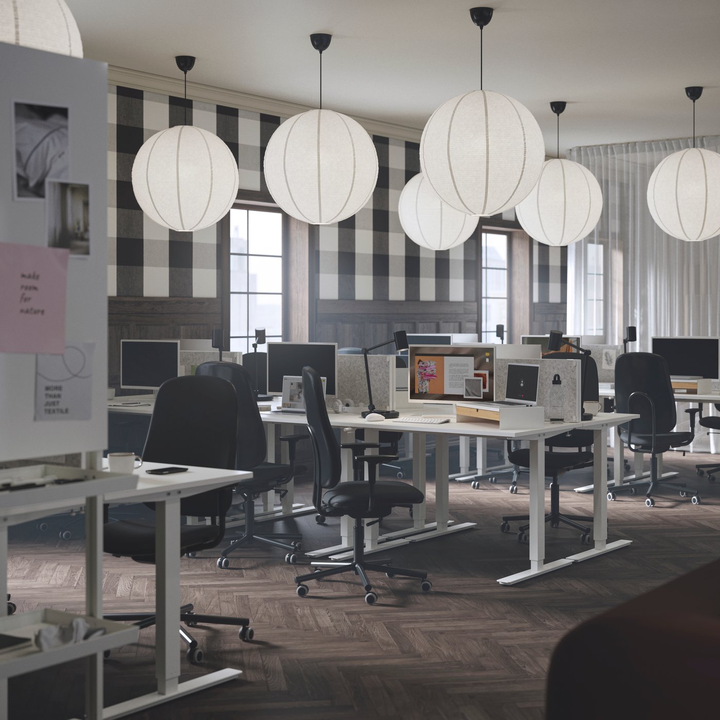 A focus zone in an office with sit/stand desks, SMÖRKULL office chairs, and GULLSUDARE pendant lampshades.