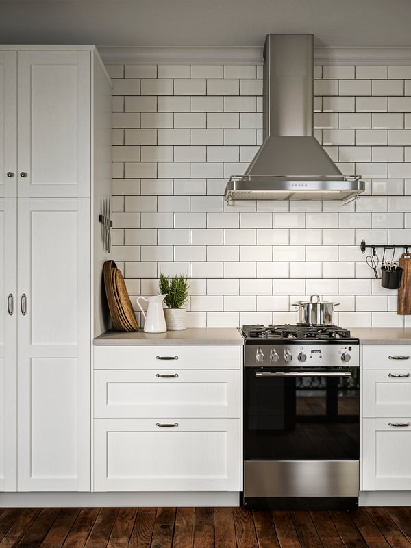 A tidy SEKTION kitchen with white tiled walls and ENKÖPING white kitchen fronts, and a range with gas cooktop.