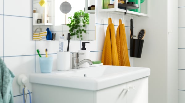 Gros plan sur un meuble-lavabo blanc accueillant divers accessoires de salle de bain.